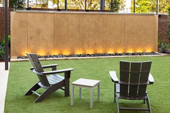 A patio with two chairs and a table on a lawn